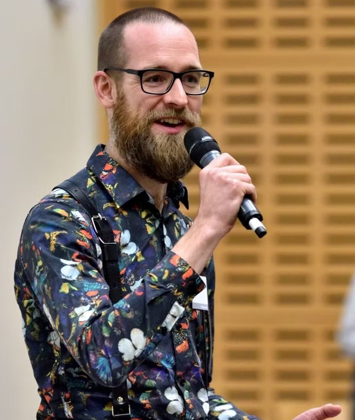 Dan Simpson speaking into a microphone at an event